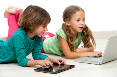 Two kids on floor with laptop and tablet.
