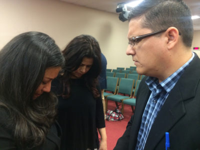 Pastor José Salcedo de la Ciudad de Dios en Coral Springs ora por una funcionaria en el lanzamiento de "Stand with God" en Broward, Florida.